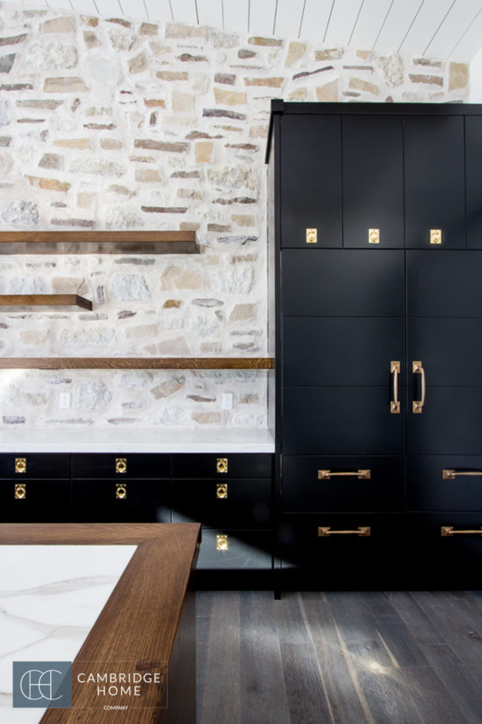 Semi transparent black kitchen cabinets and rock wall kitchen back splash in an industrial farmhouse kitchen